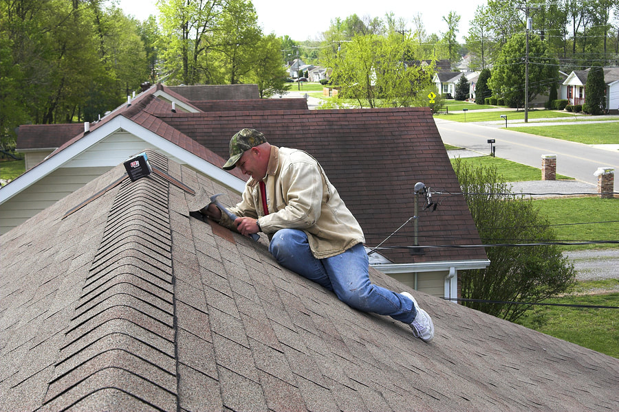 man on the roof hammering a nail